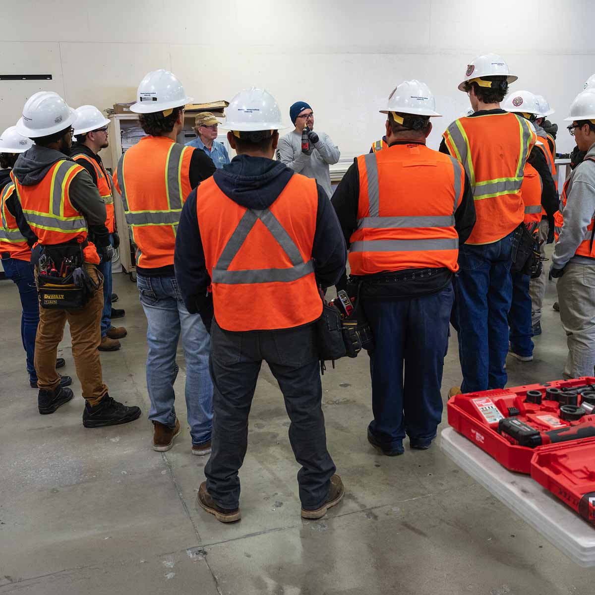 Electrician Trainee students standing around the istructor as he speake to them.