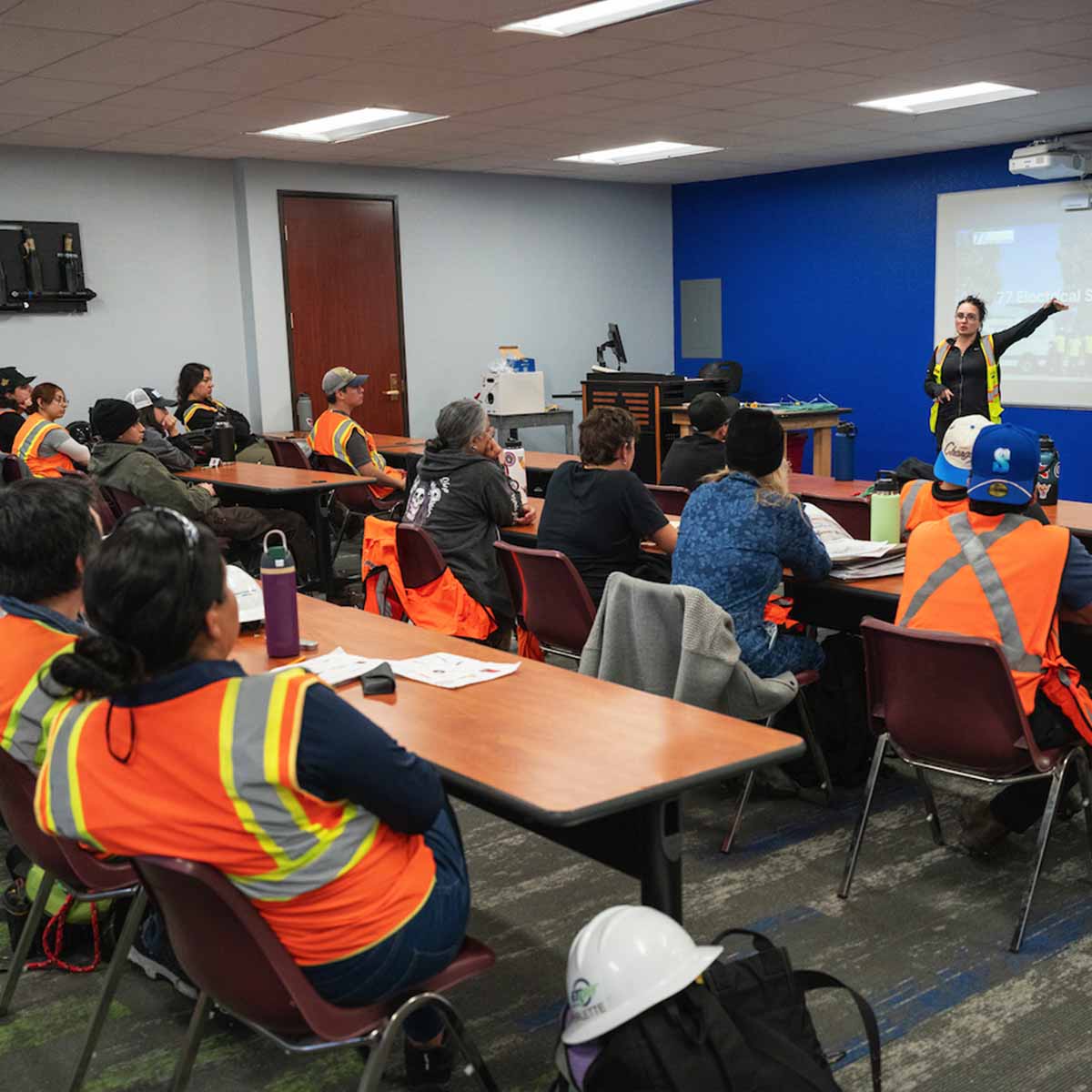 Femail instructor teaching Electrician trainees in a classroor.