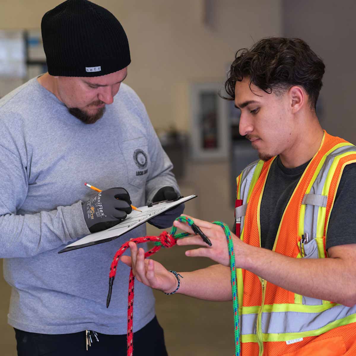 Electrician Trainee having the knott he tied graded by an instructor.