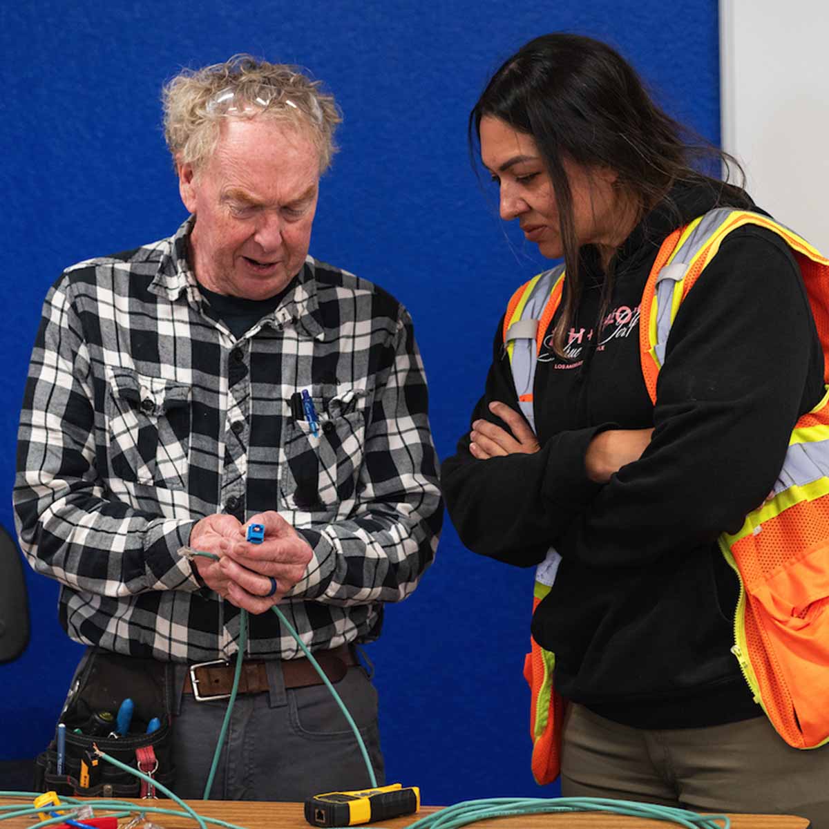 Instructor explaining cable connections to a femail Electrician Trainee in class